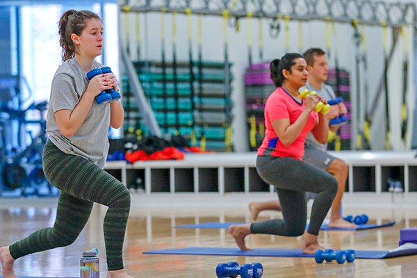 Three students exercising with weights