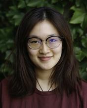 Chenwei Yan, an Asian woman with shoulder-length hair and glasses looks at the camera and smiles.